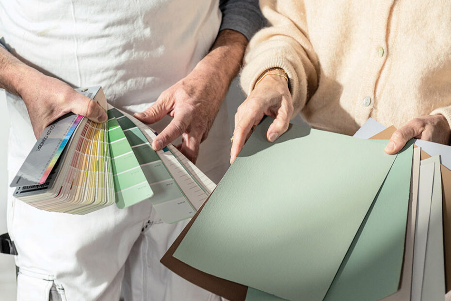 A professional painter holds a colour fandeck, whilst a potential customer looks through large colour samples.