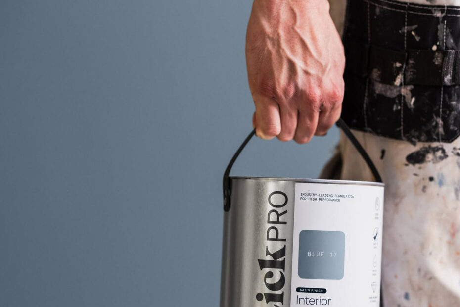 Decorator holding a can of LickPro Interior Wood & Metal paint by their side.